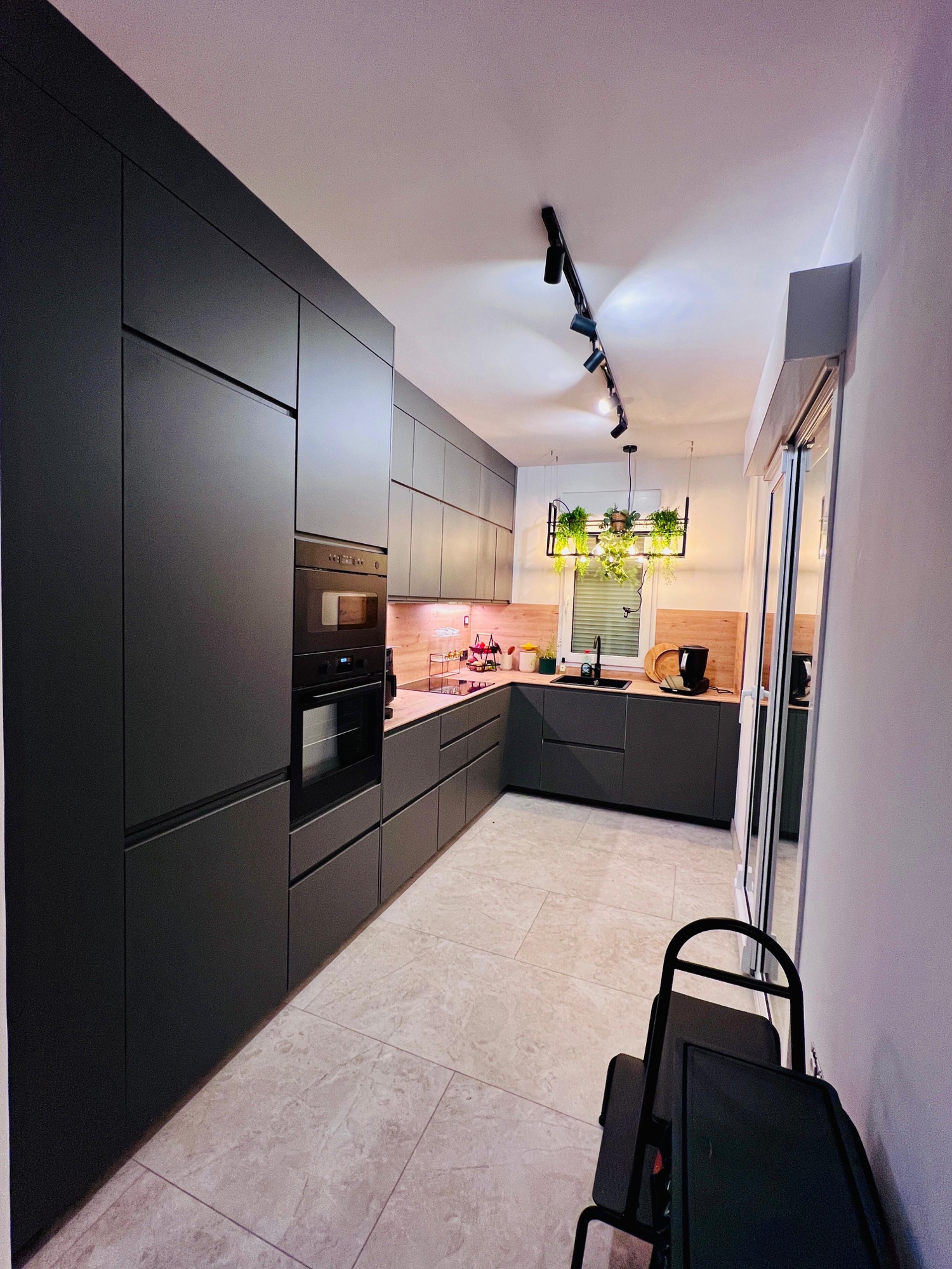 Cocina con muebles oscuros, cajones y electrodomésticos integrados.