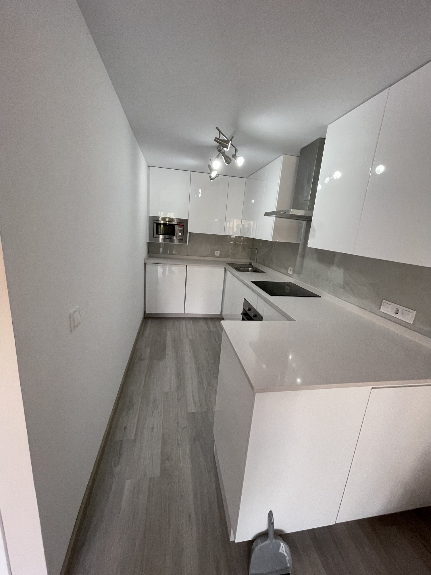 Cocina con muebles blancos, encimera y distribución en L.